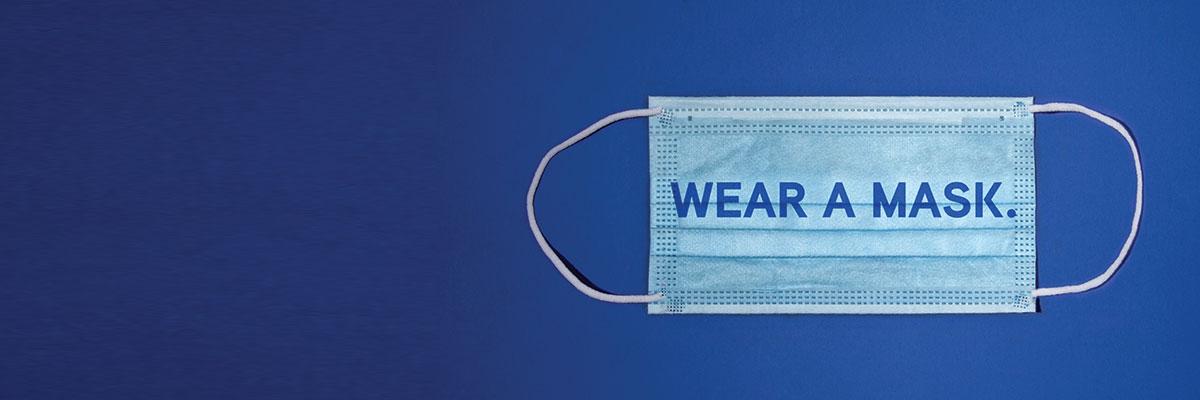 Wear a Mask For All the Things You Love. A blue surgical mask with the words "Wear a mas." overlayed on it.